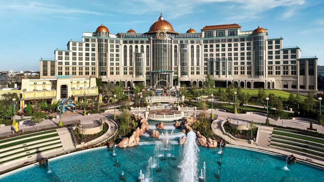 Exterior view of Helios Grand Hotel, a Mediterranean-inspired hotel with a large fountain and landscaped grounds, located at Universal Orlando's Epic Universe.